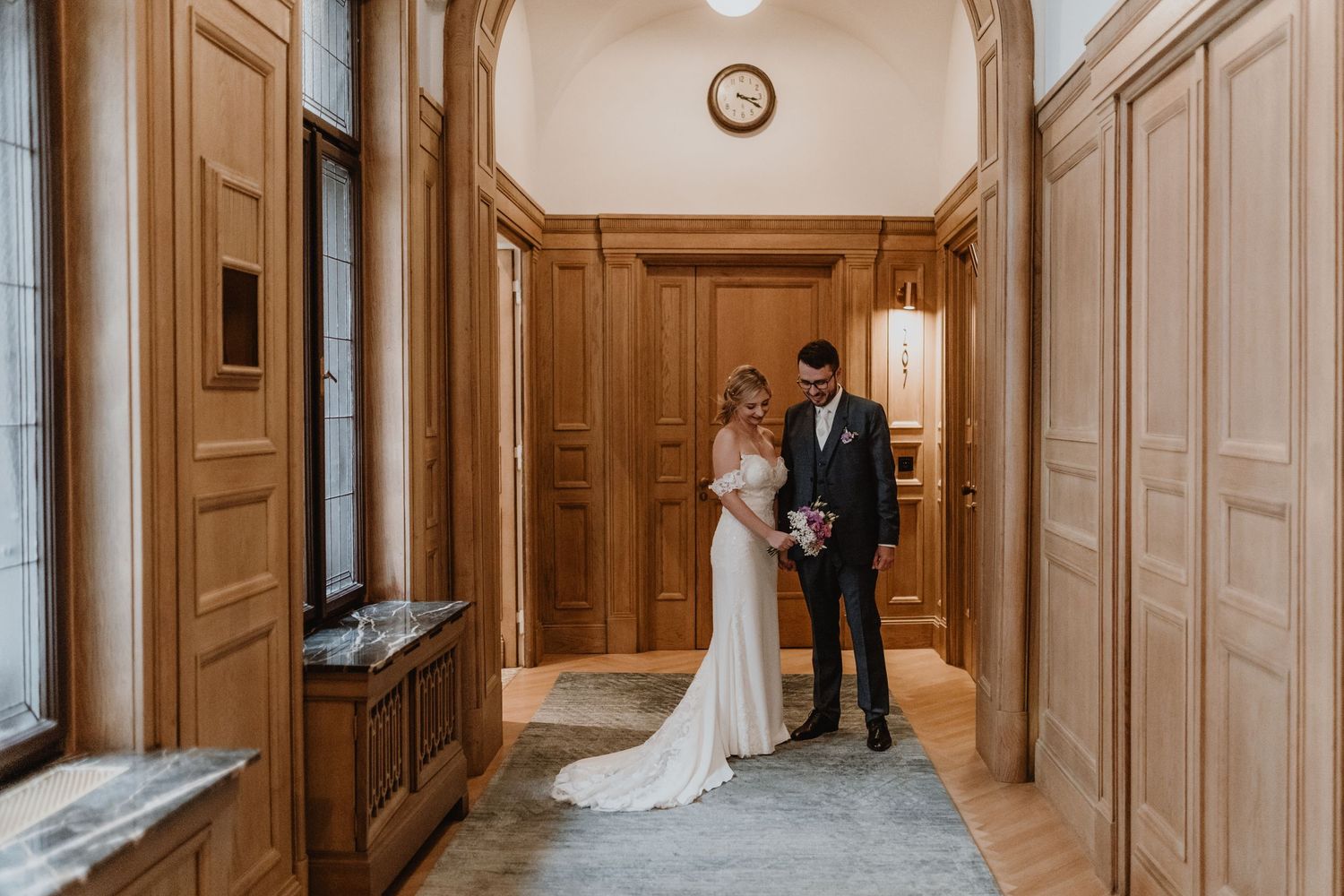 Newlywed couple walking together on tree-lined gravel path.