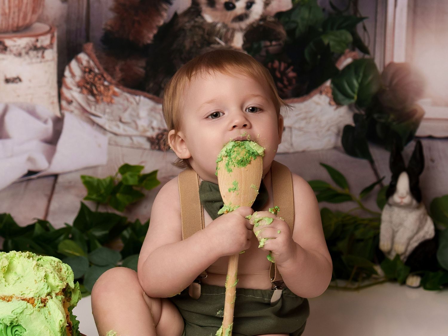 Rustic woodland cake smash photo with green frosting and nature-inspired backdrop.