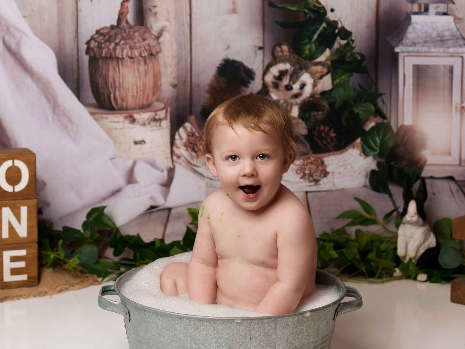 Festive cake smash photo shoot with galvanized tub and woodland-themed decorations.