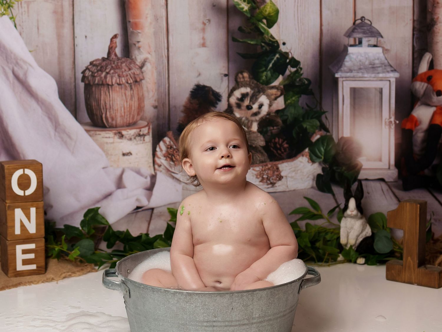 Woodland-themed photo session with vintage metal tub and rustic wooden backdrop.