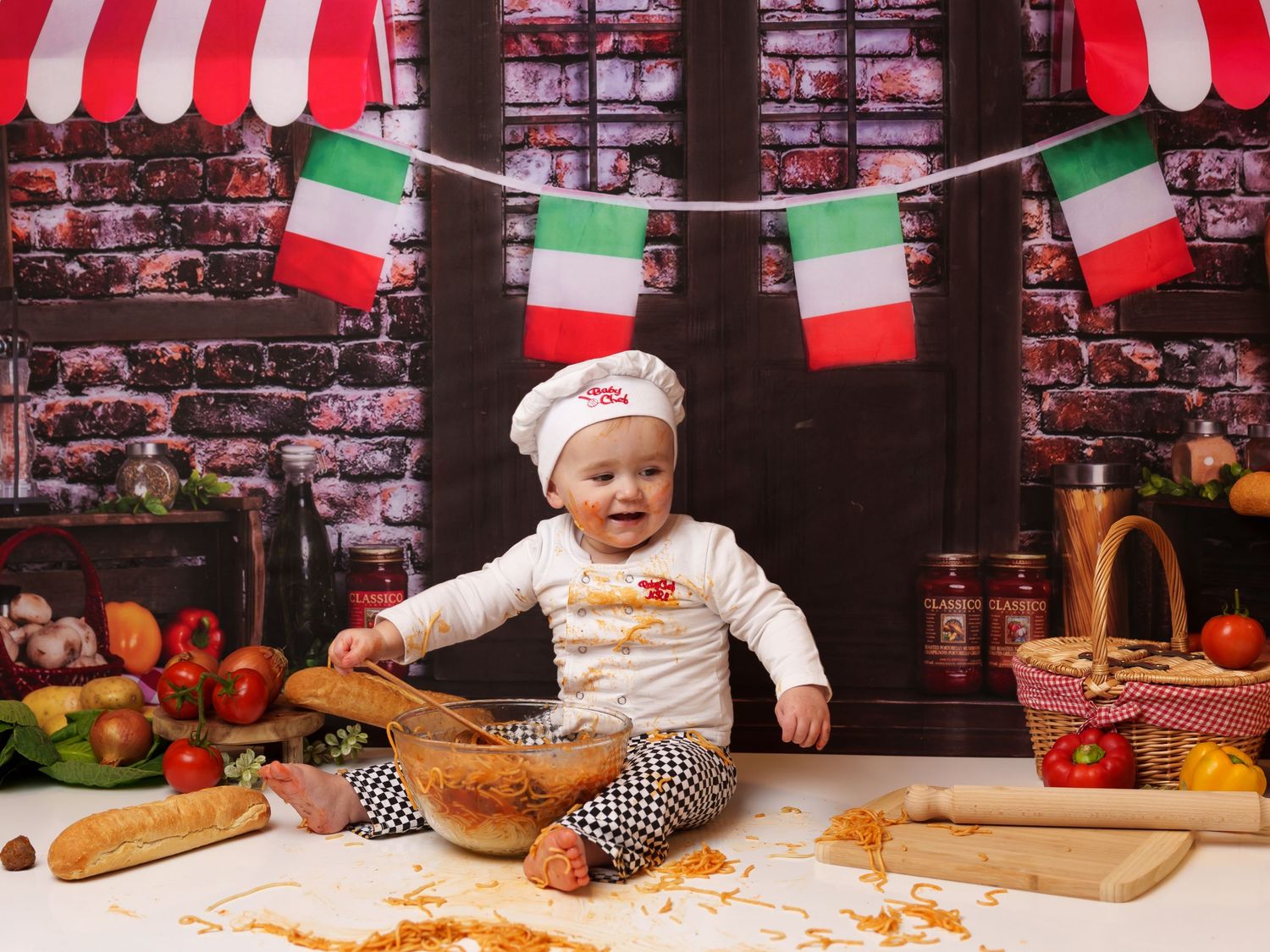 Messy spaghetti smash session with Italian flags and red striped awning backdrop.