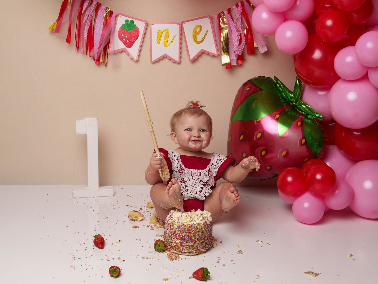 Strawberry-themed first birthday with cake mess and festive banner decorations.