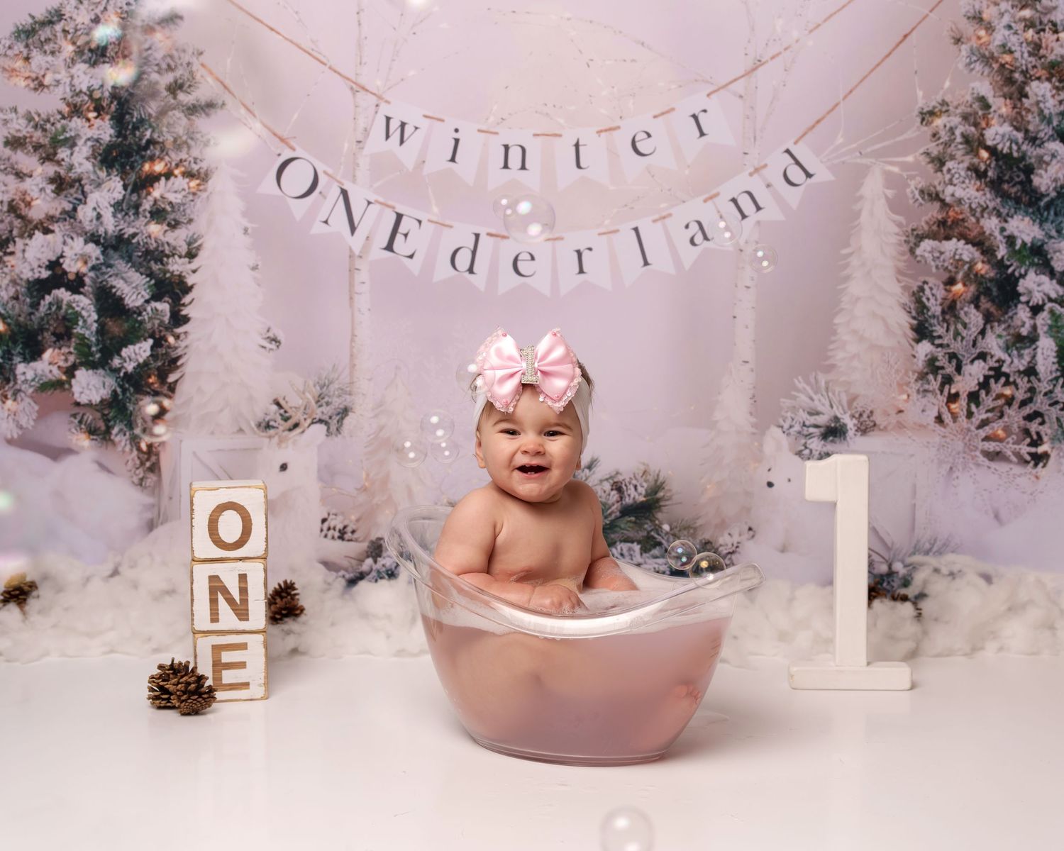 Winter themed first birthday setup with wooden blocks spelling ONE and decorative bath.