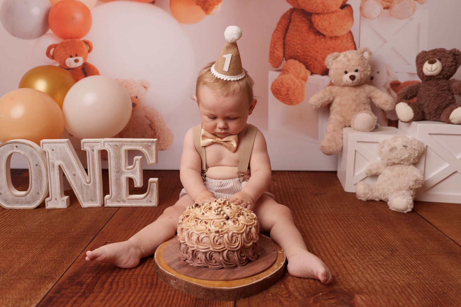 Rustic first birthday setup with smash cake, balloons, and teddy bear decorations.
