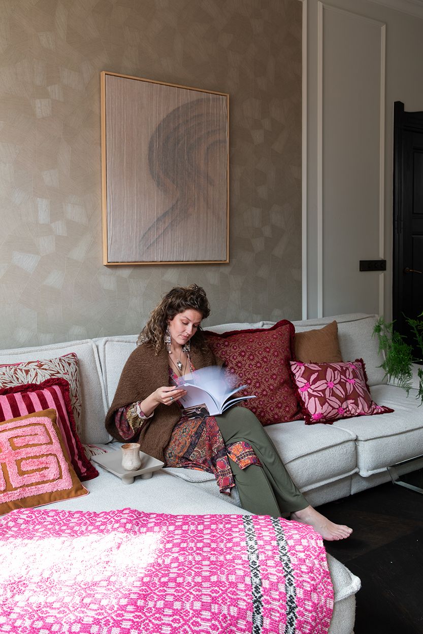 Interieurfoto voor een binnenkijker bij een oud herenhuis in Den Bosch. Bewoner zit op de bank met een kop koffie en woontijdschrift.