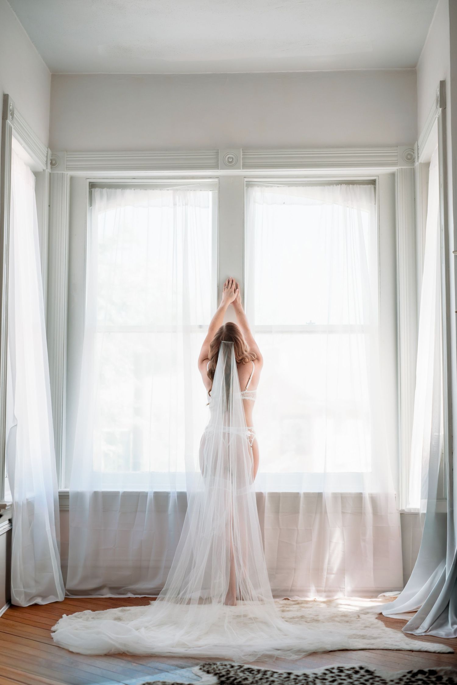 Blonde woman poses with her veil during a bridal boudoir session in downtown Cape Girardeau