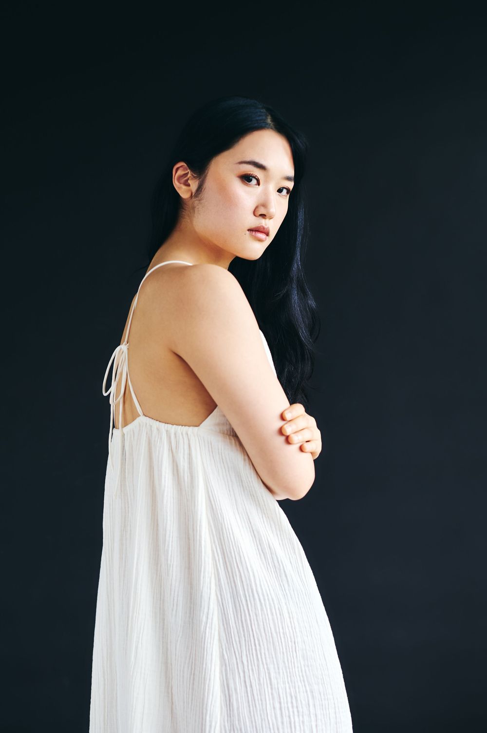 Minimalist fashion portraits featuring flowing white dress against dramatic black backdrop.