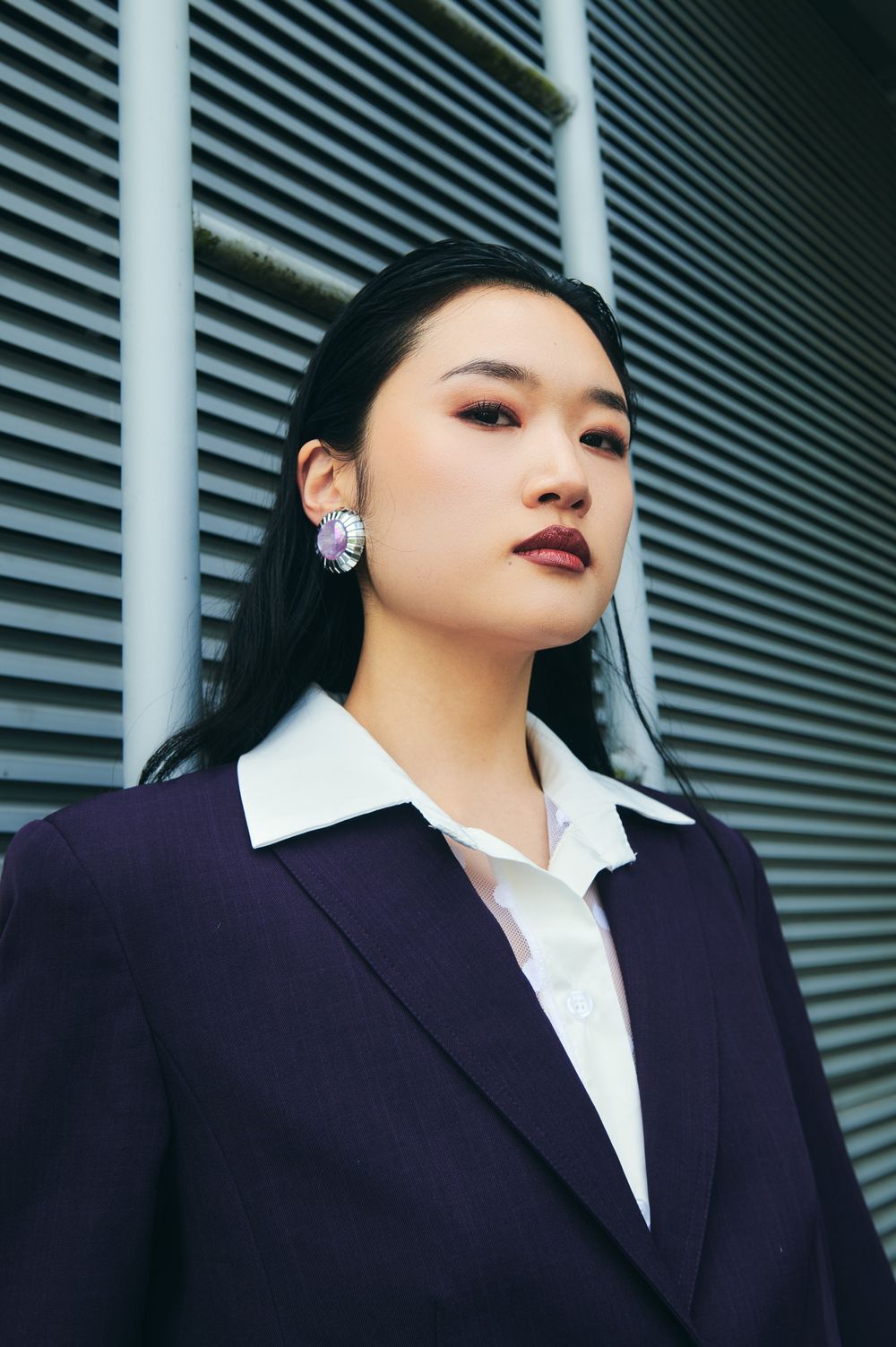 A fashion portrait series showing different angles of a person in a navy blazer and white collared shirt against a striped wall.