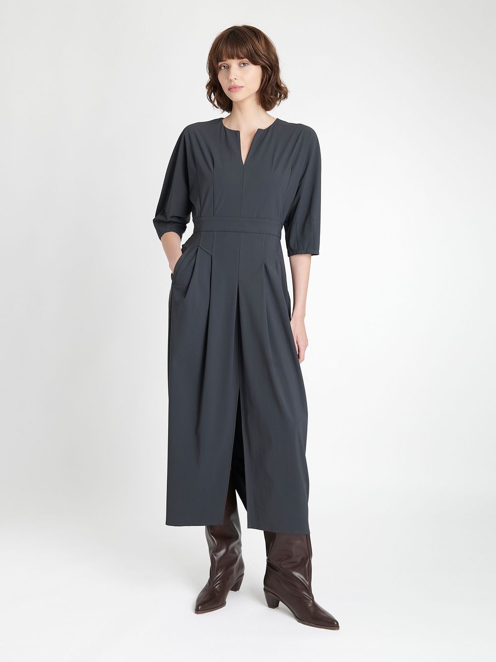 A dark gray midi dress with short sleeves and front pleating detail shown from multiple angles with brown boots.