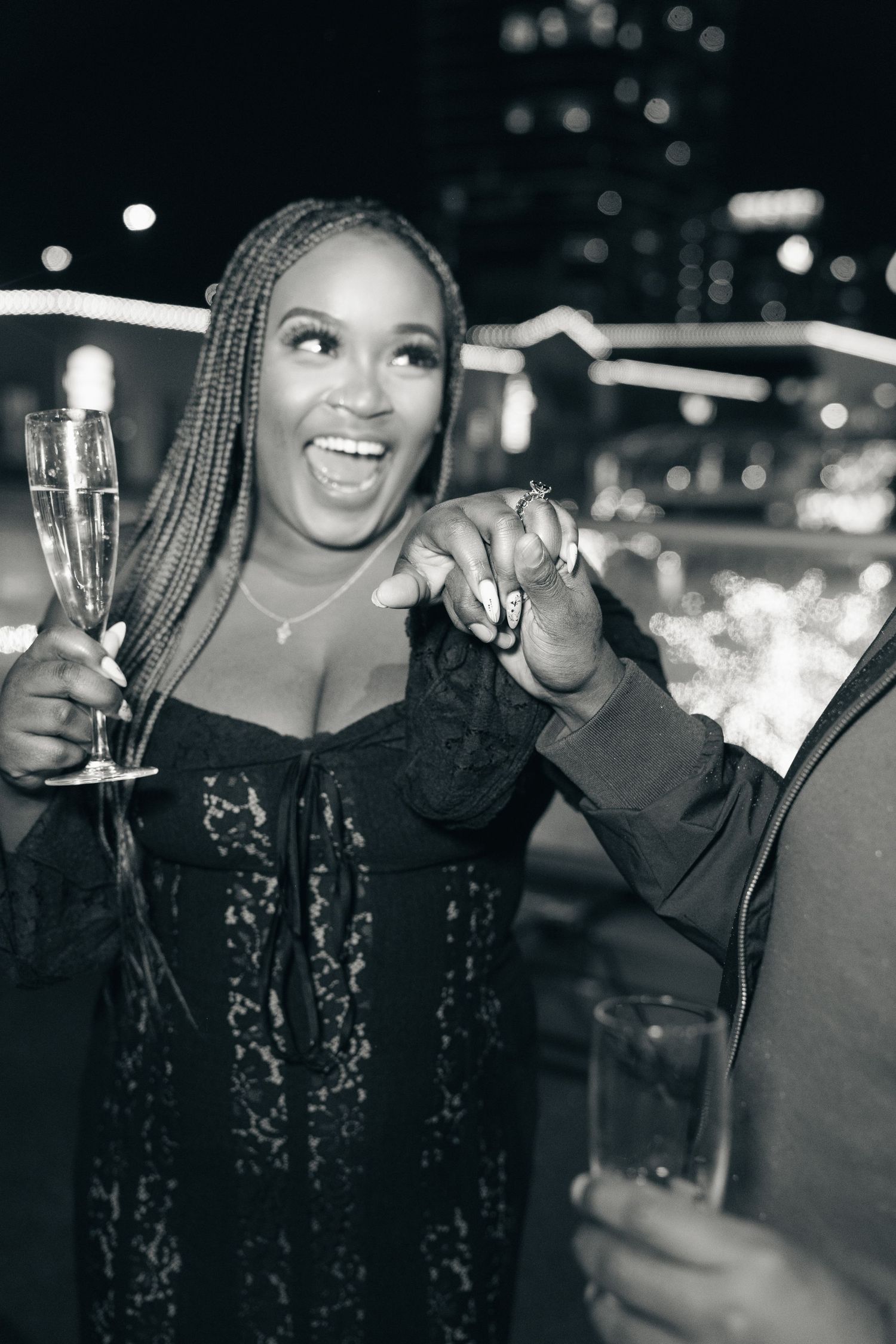 Person in a black lace dress enjoying a night out with champagne and demonstrating joyful excitement at a party.