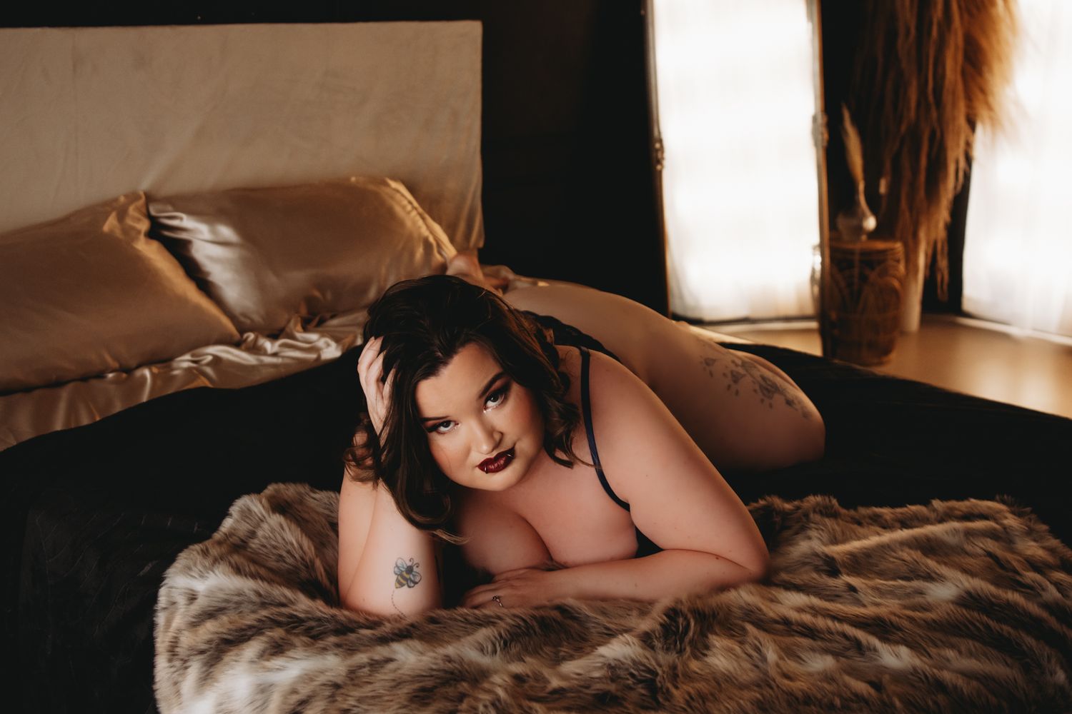 woman with dark hair laying on bed in black lingerie