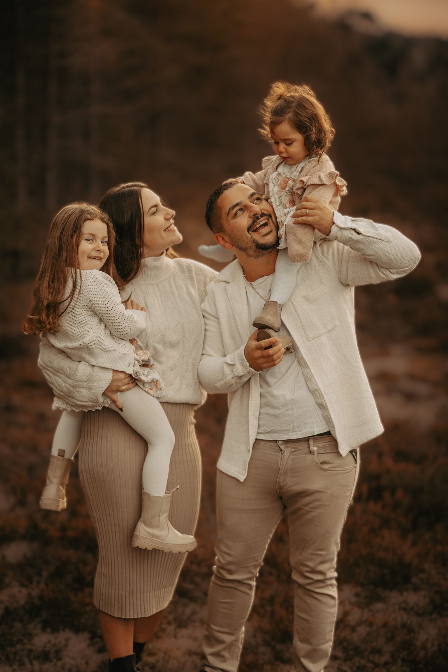 A sweet moment between parent and baby in white outfits against a dreamy natural backdrop.
