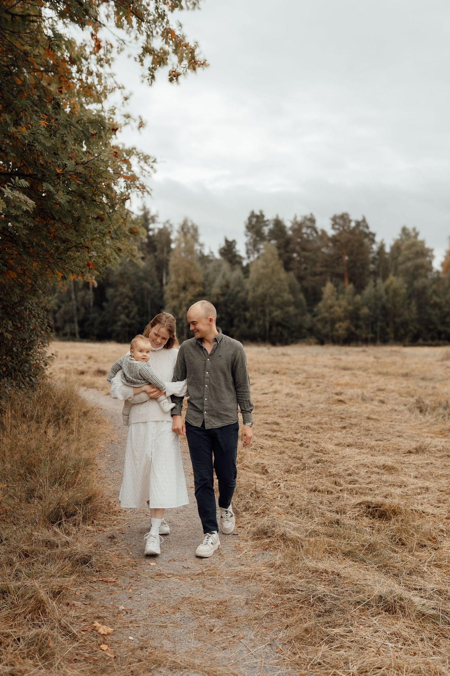 A sweet moment between parent and baby in white outfits against a dreamy natural backdrop.