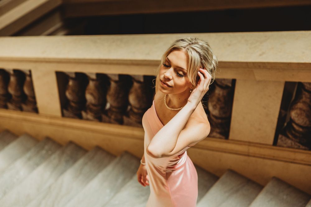 A person poses on concrete steps in casual attire with dramatic lighting.