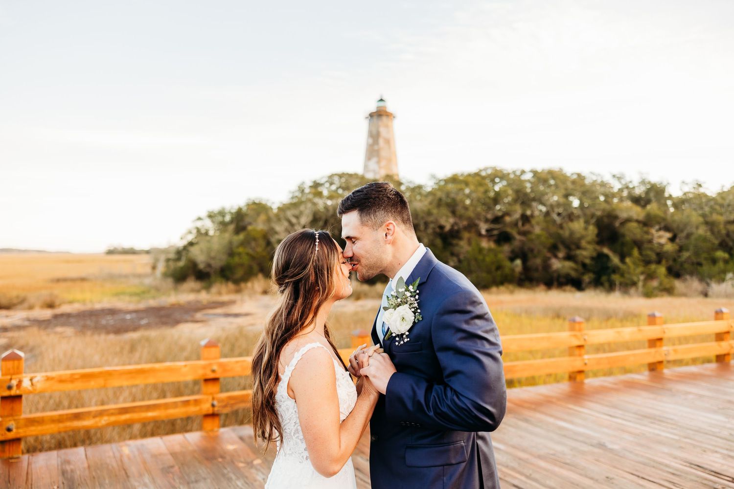 A couple shares a romantic moment on a wooden boardwalk during a sunset photo session.