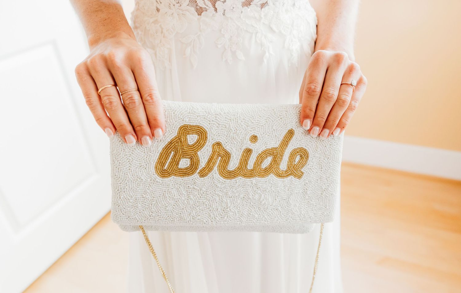 Close-up details of a white lace wedding dress and matching accessories in soft natural lighting.