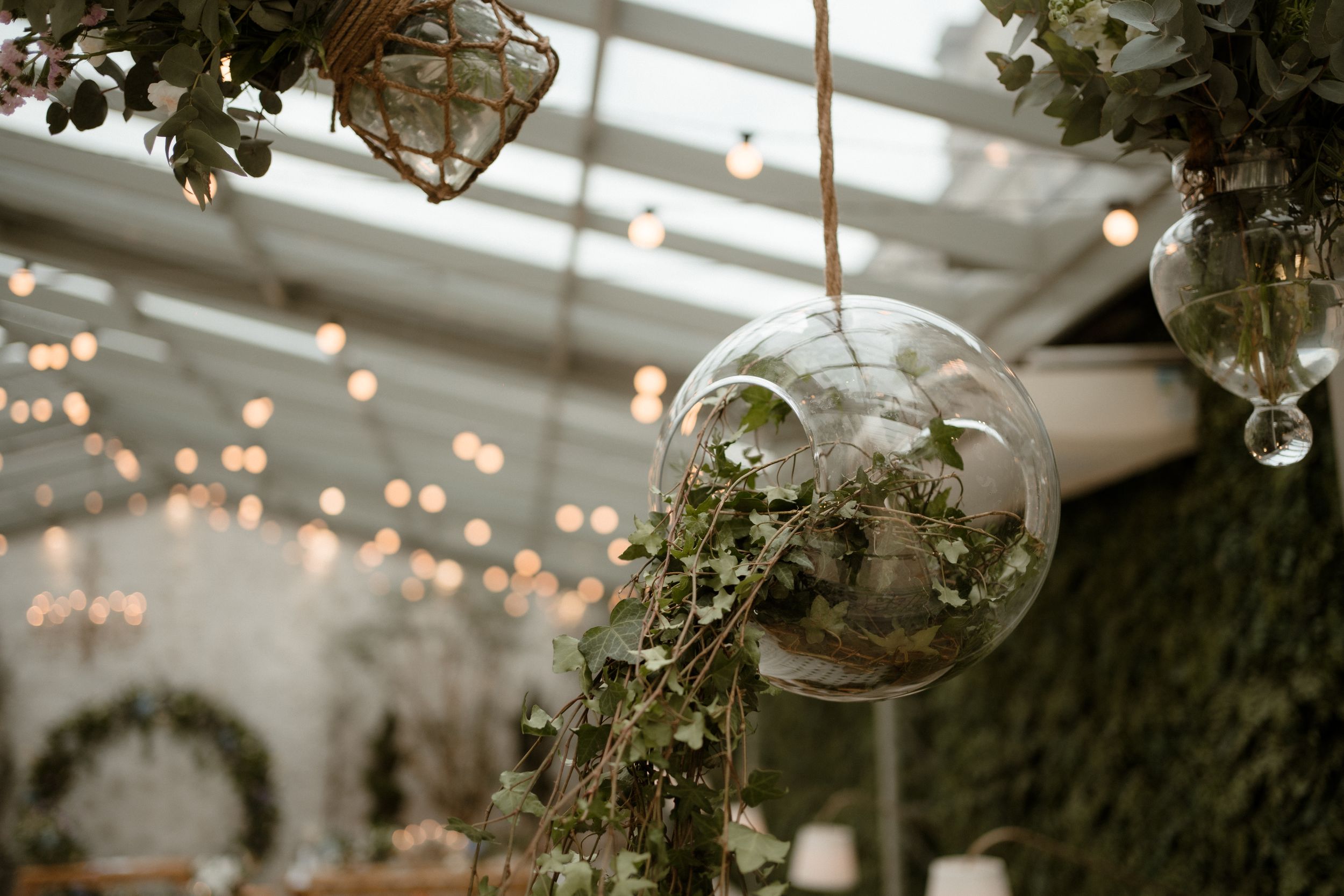 Glass orb decorations hanging among lush greenery with twinkling lights.