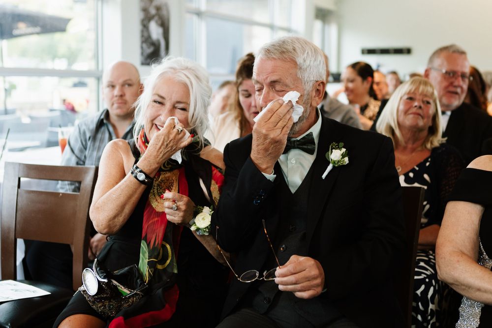 A group of elderly people enjoying a social gathering in a bright indoor space, laughing and interacting with each other.