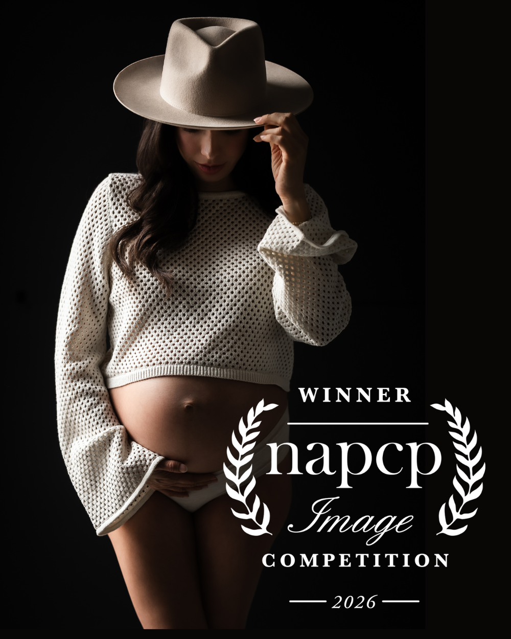 Pregnant woman in white sweater and hat cradling baby bump, NAPCP Image Competition Winner 2026.