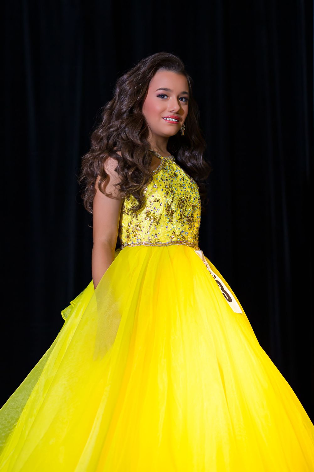 Close up of bright yellow pageant ball gown with detailed beaded bodice.