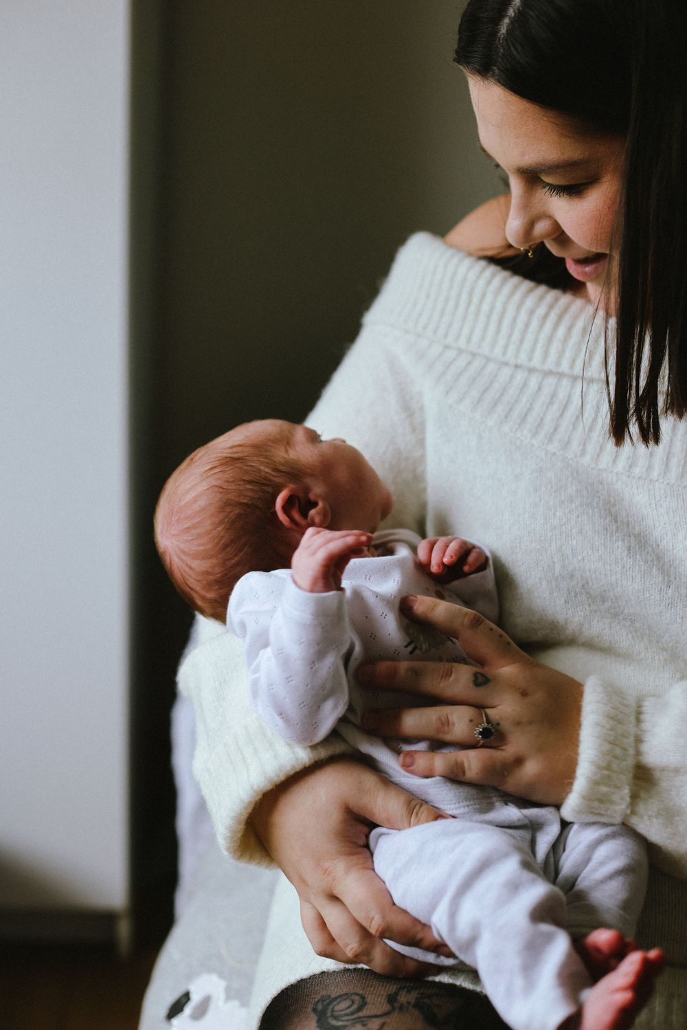 An intimate moment between parent and infant as they cuddle in cozy white knitwear.