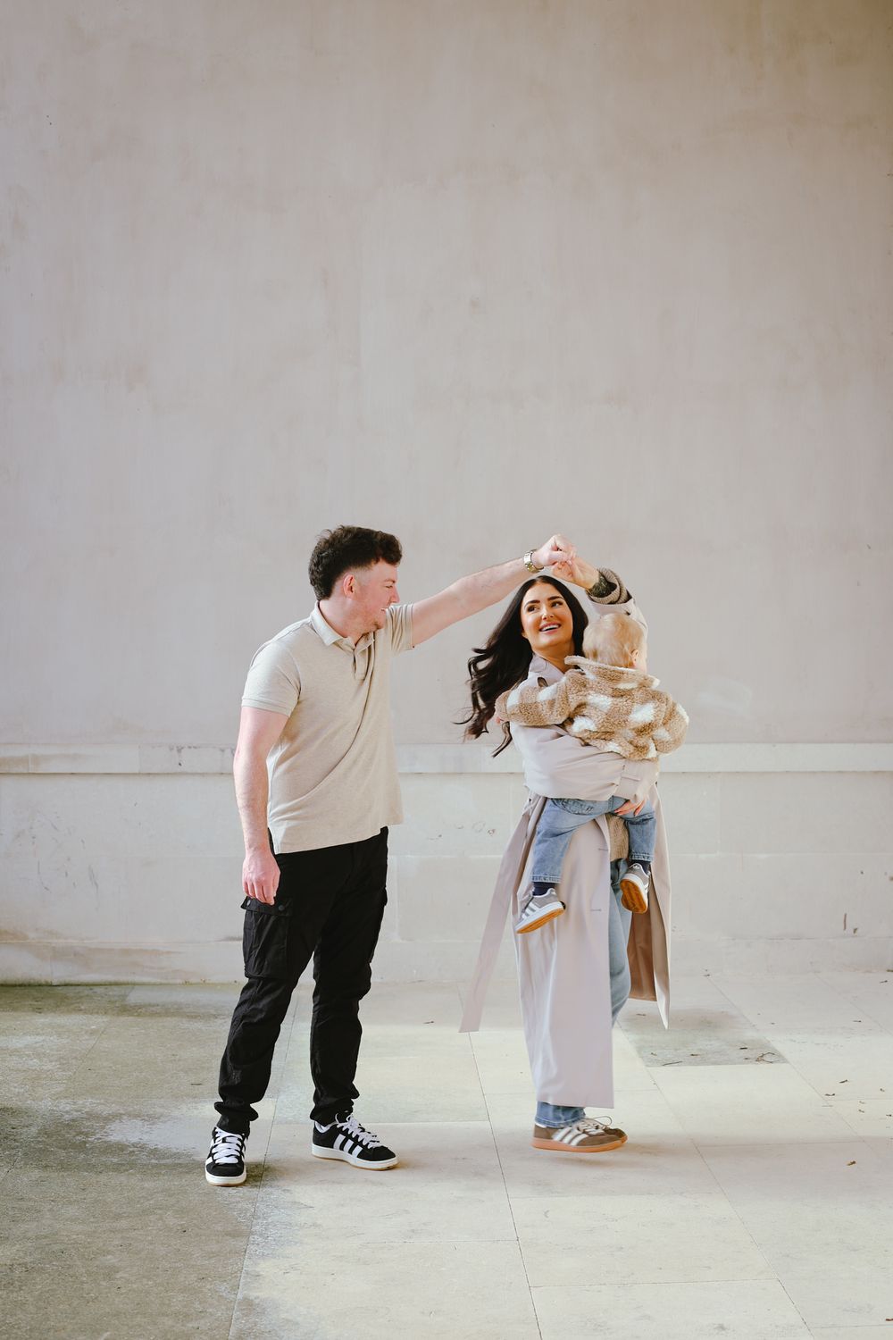 A playful dance moment between a couple with their baby in an industrial space.