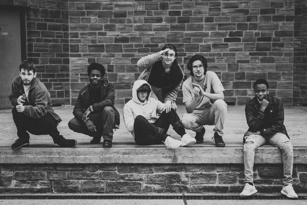 A sequence of black and white photos showing people sitting on a brick wall in different playful poses.