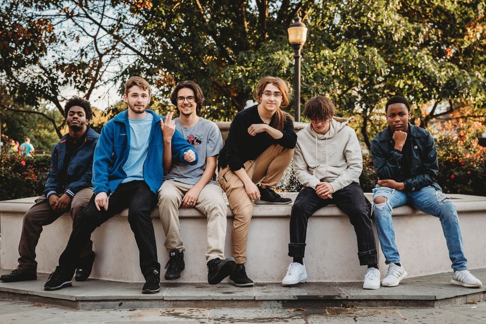 A group of people sitting casually on concrete steps during a sunny autumn day.