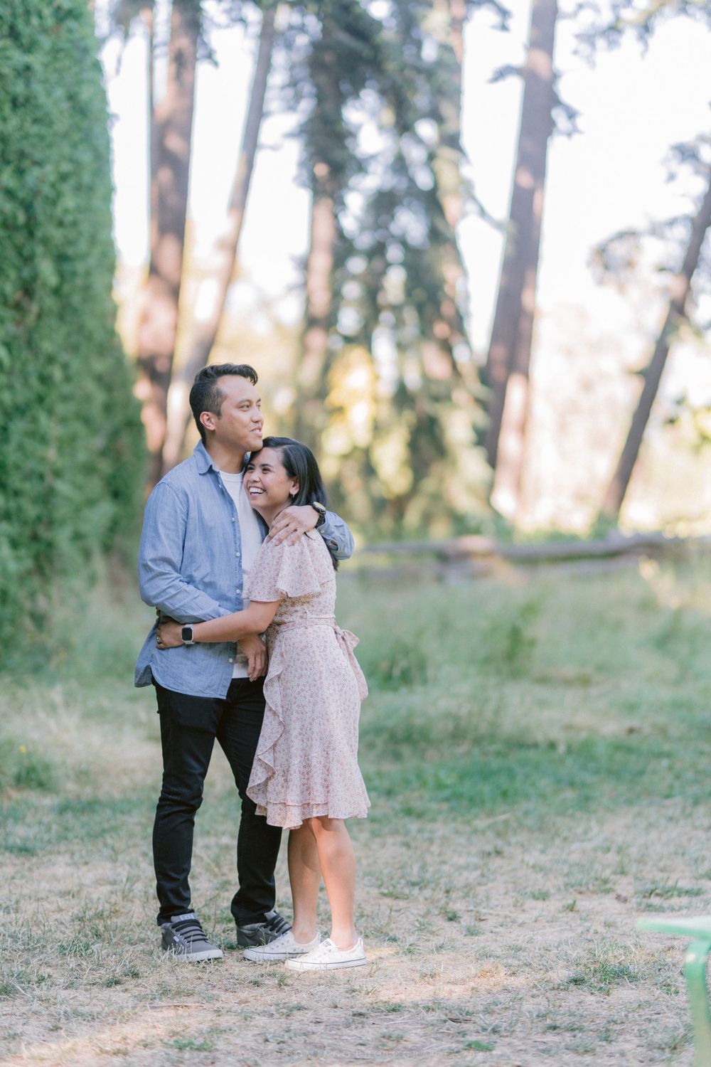 A couple embraces outdoors in a romantic forest setting during golden hour.