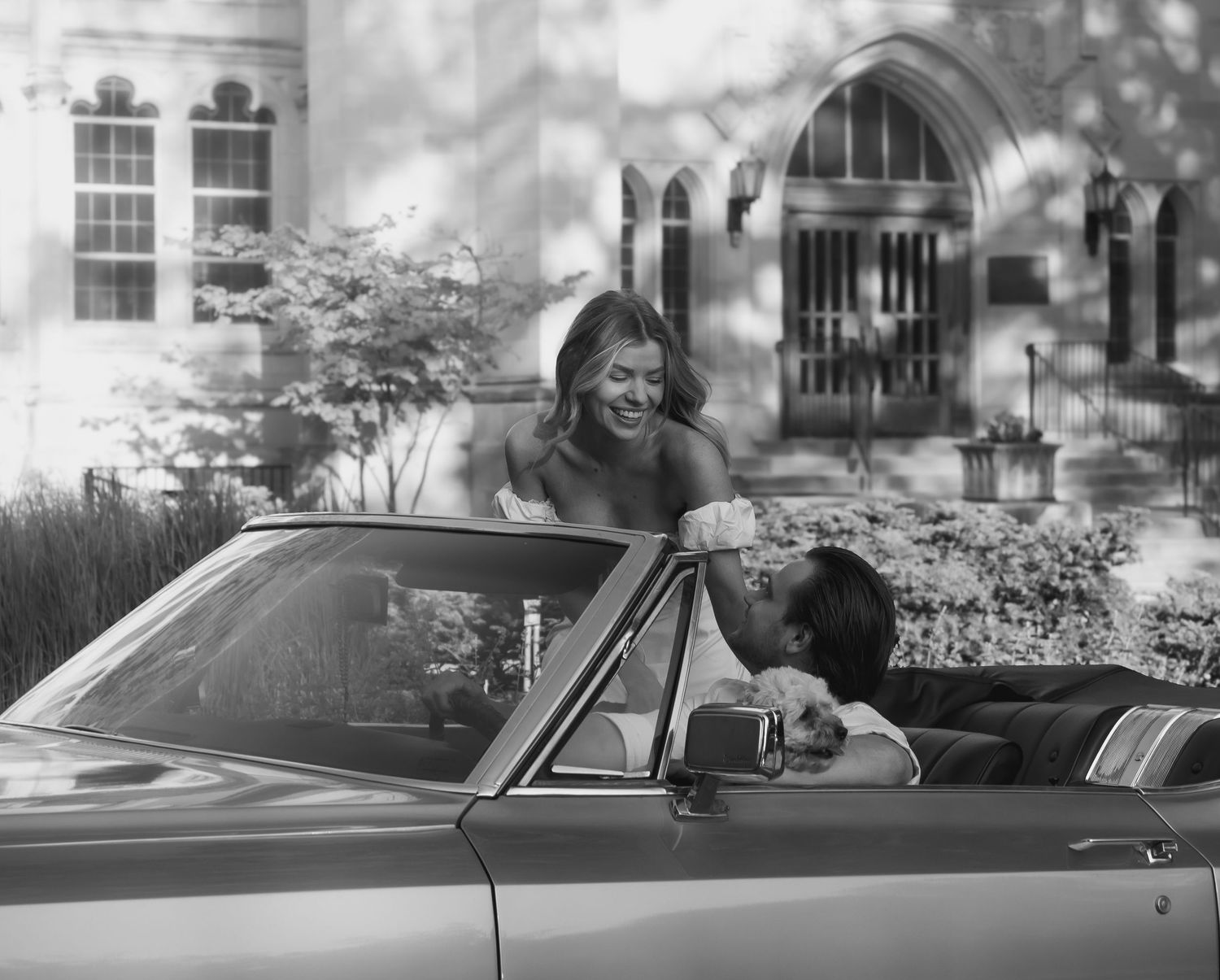 A couple shares a carefree moment in a vintage convertible car on a sunny day.