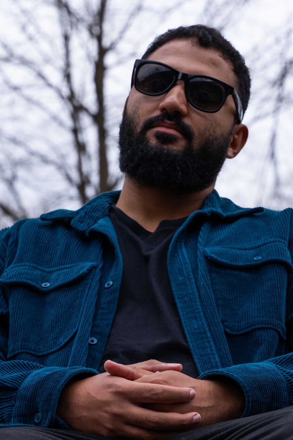Man in blue denim jacket and sunglasses photographed in multiple casual poses against winter trees.