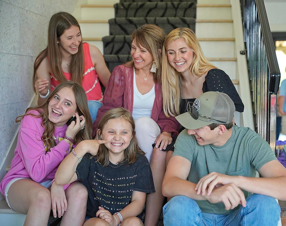 Friends lounging and laughing together on outdoor steps during a casual gathering.