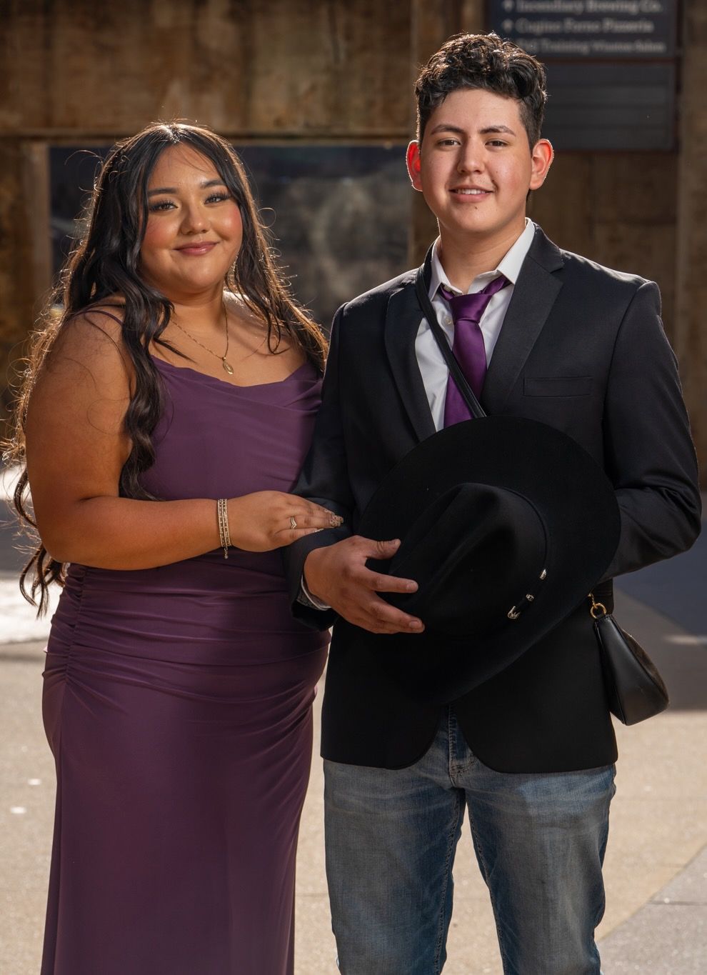 Couple in formal attire posing together with black hat.