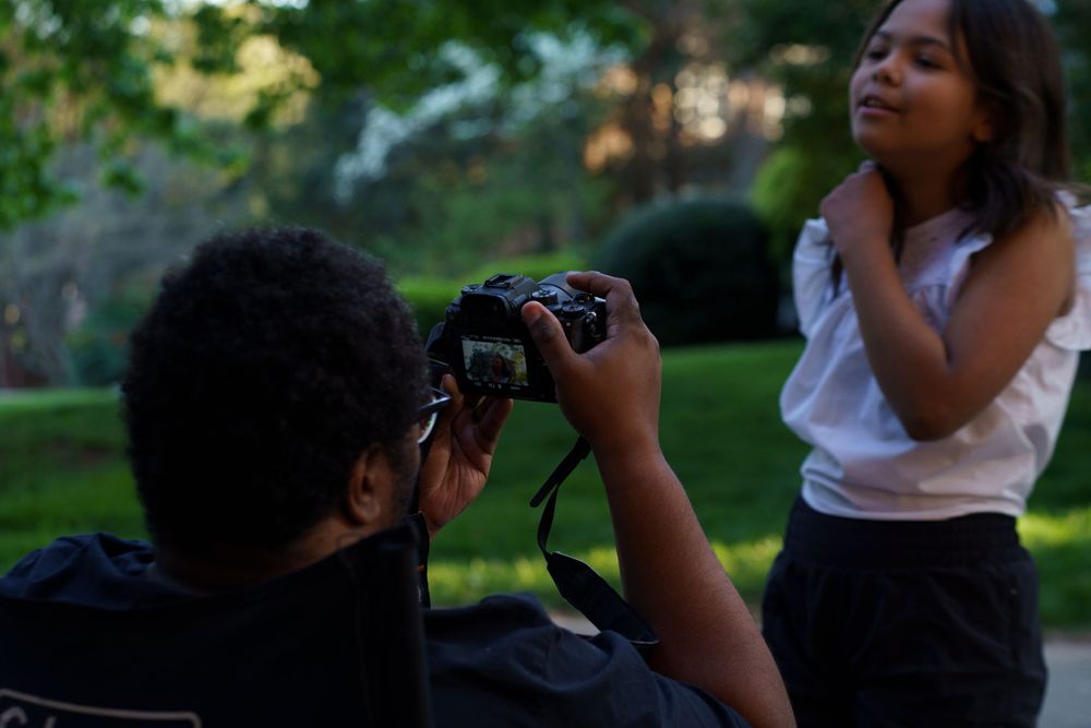 People taking photos outdoors in a park setting during golden hour.