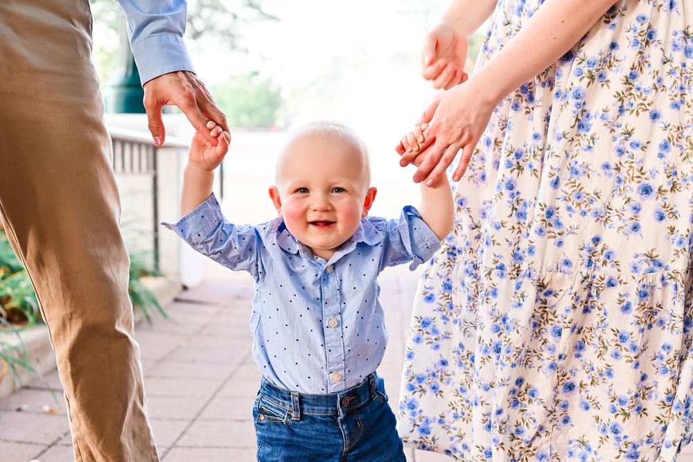 Baby boy holding hands with his mom and dad at the train station in Lafayette, IN.