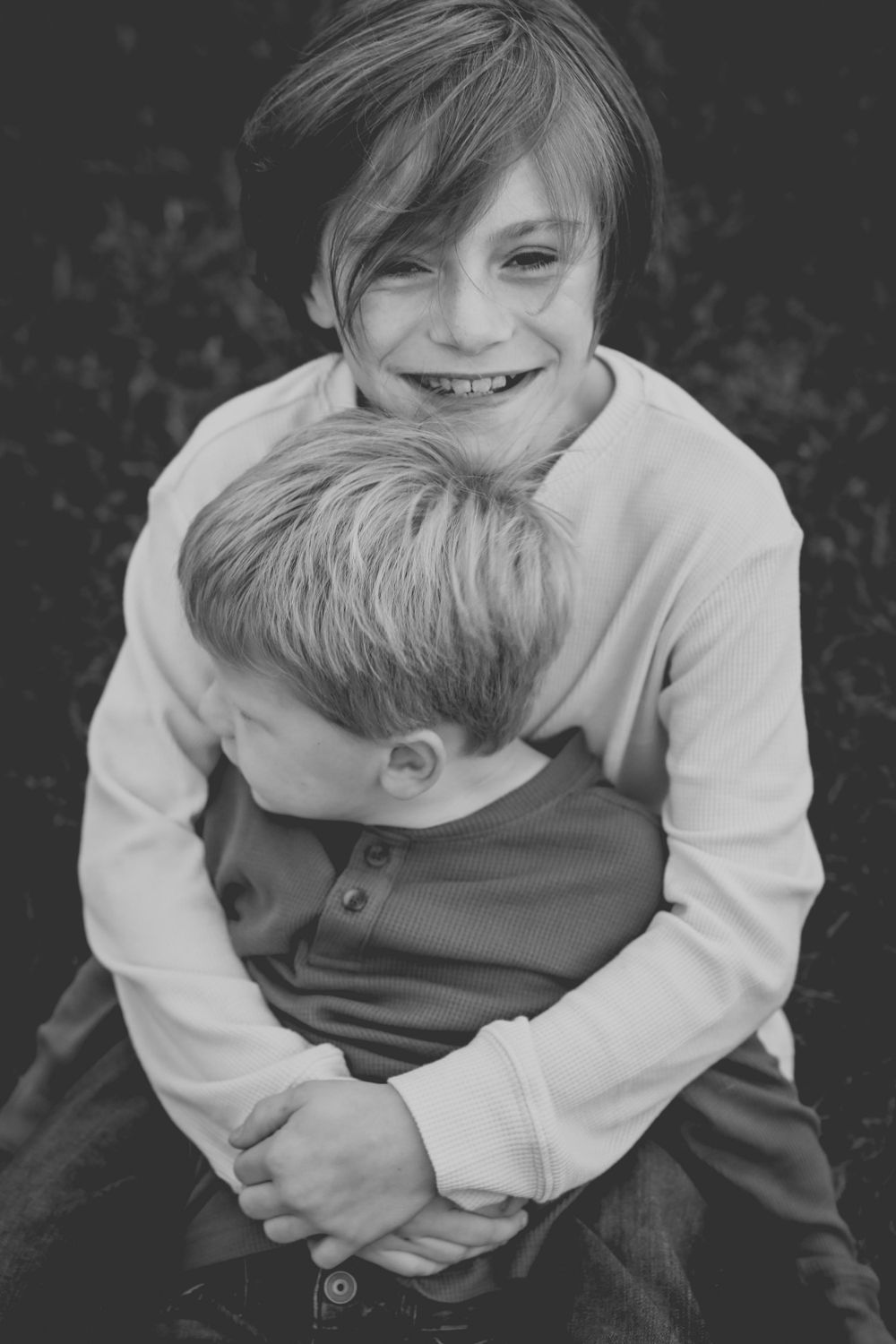 Black and white image of young brothers embracing.