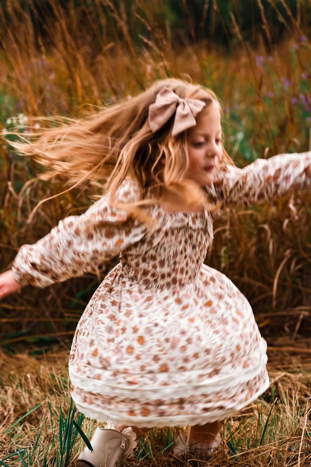 Little girl twirling around in prairie.
