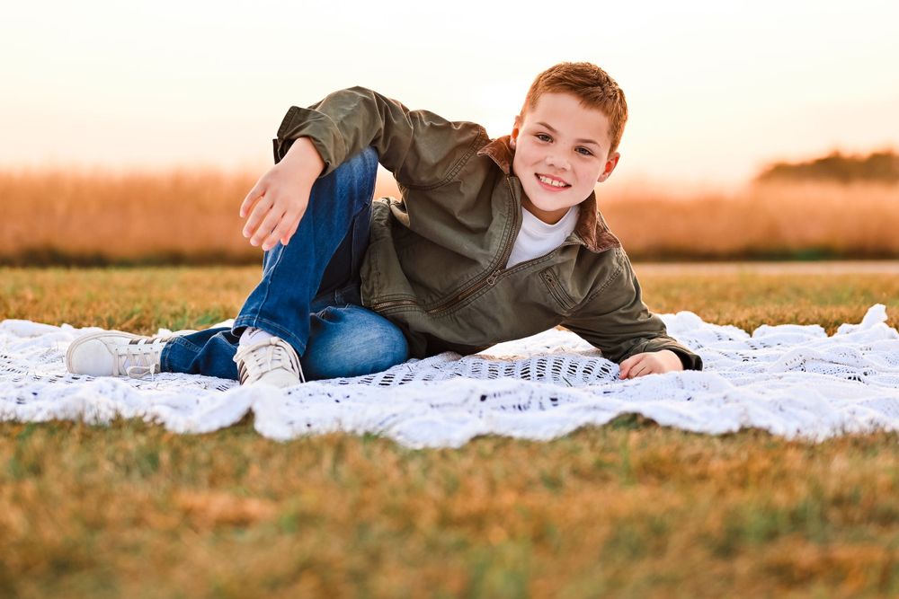 Young boy poses on ground for photographer, melissa j. conwell photography.