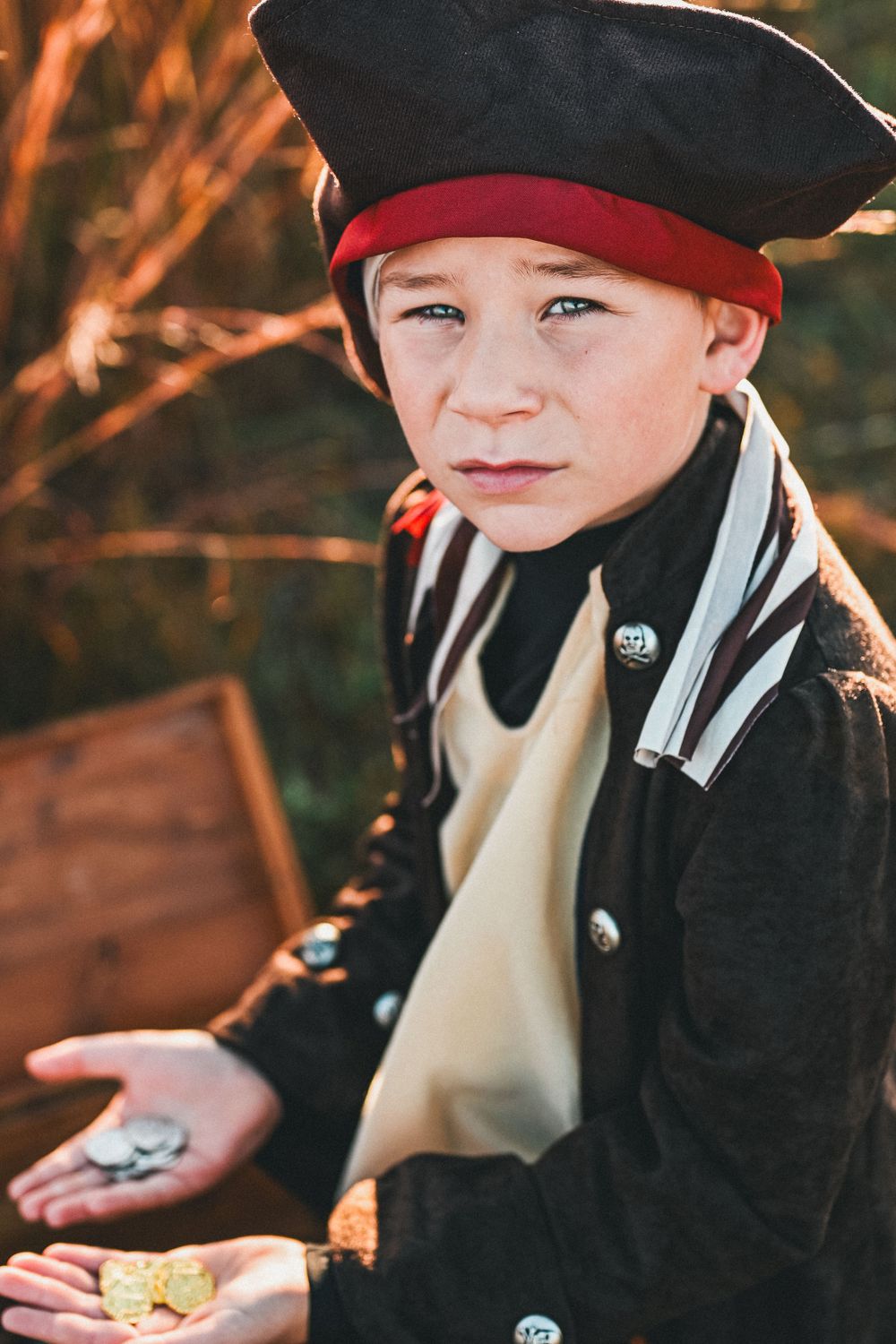 Little boy dressed up as pirate with treasure chest.