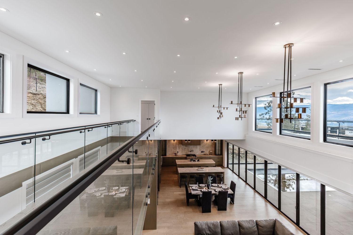Modern living room with vaulted ceiling, tan leather couches, and wooden stair railings.