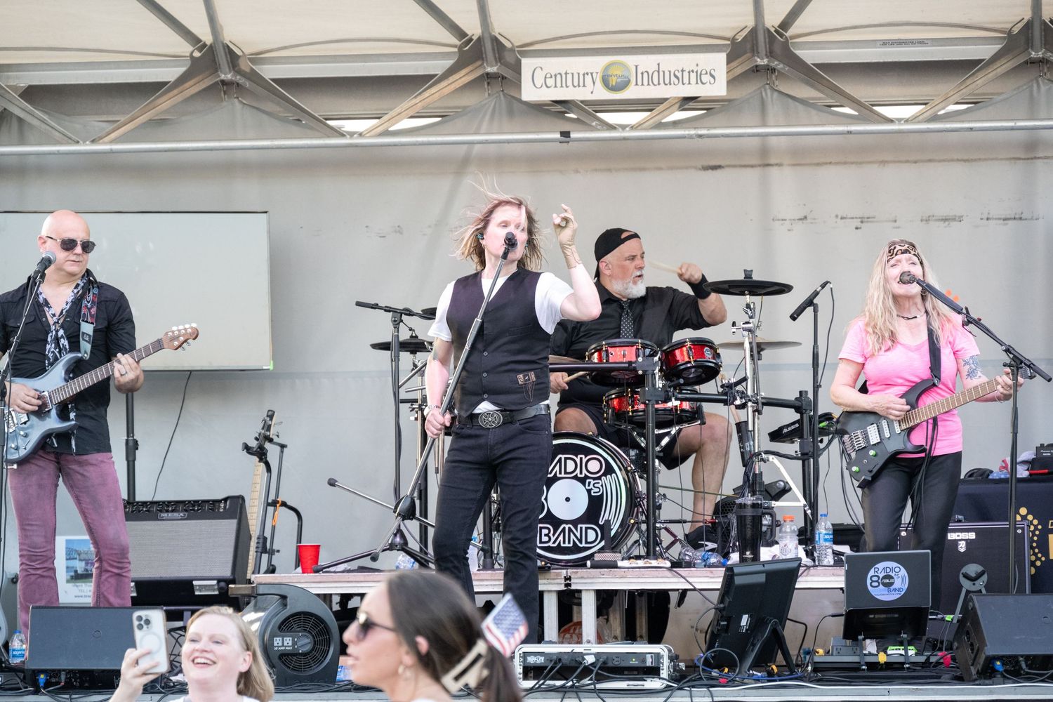 Band plays energetic set on festival stage with full musical setup including drums and guitars.