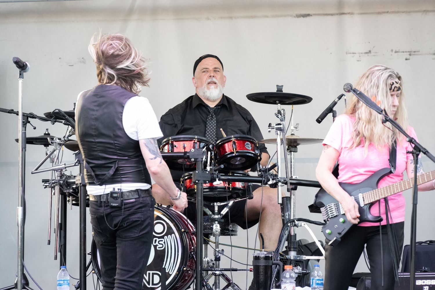 Band members interacting during a live performance with drums and instruments on stage.