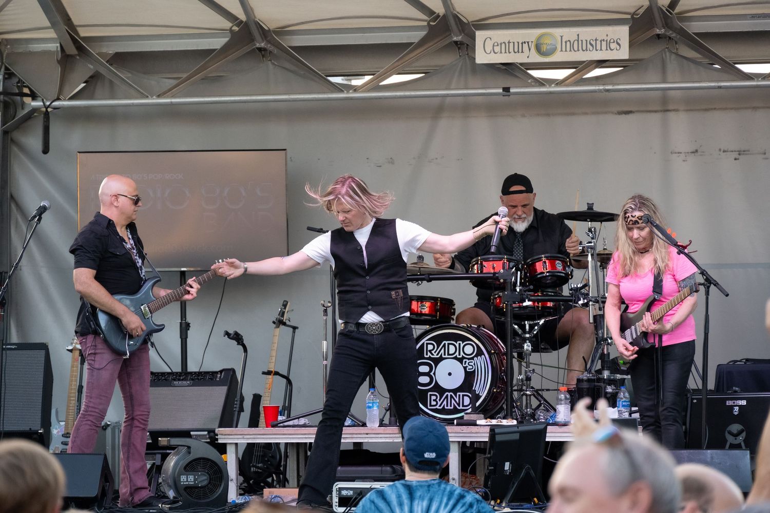 Energetic live music performance on an elevated outdoor stage with festival lighting and equipment.