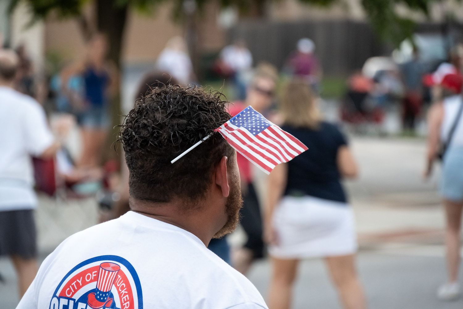 A crowd member displays a small American flag during an outdoor summer celebration.