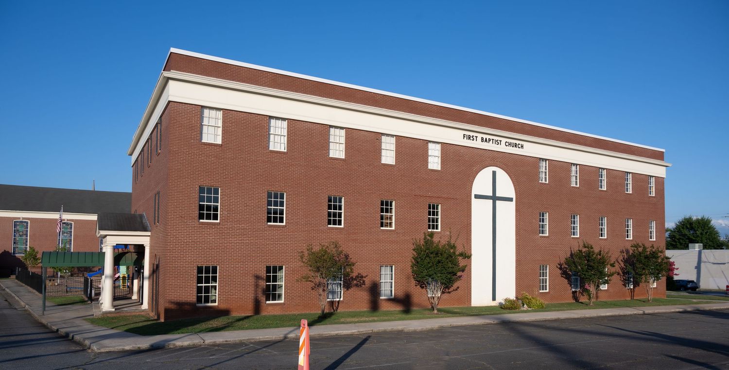 Two-story red brick commercial building with white columns and arched window.