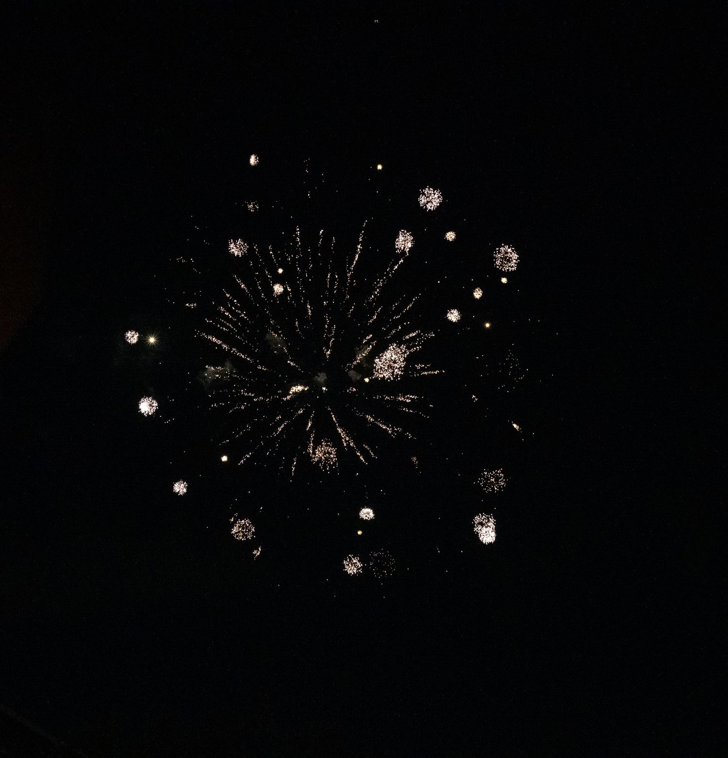 Multiple small white firework bursts create a scattered pattern in the darkness.