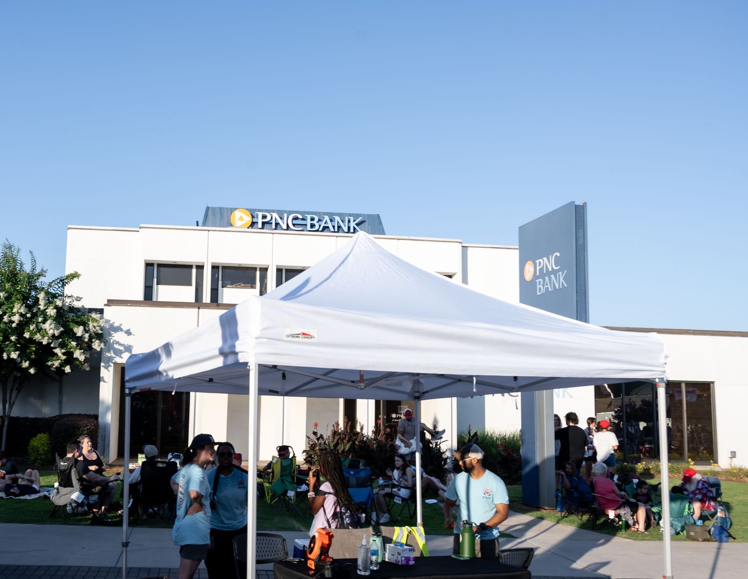 Bank building with white tent and outdoor gathering setup.