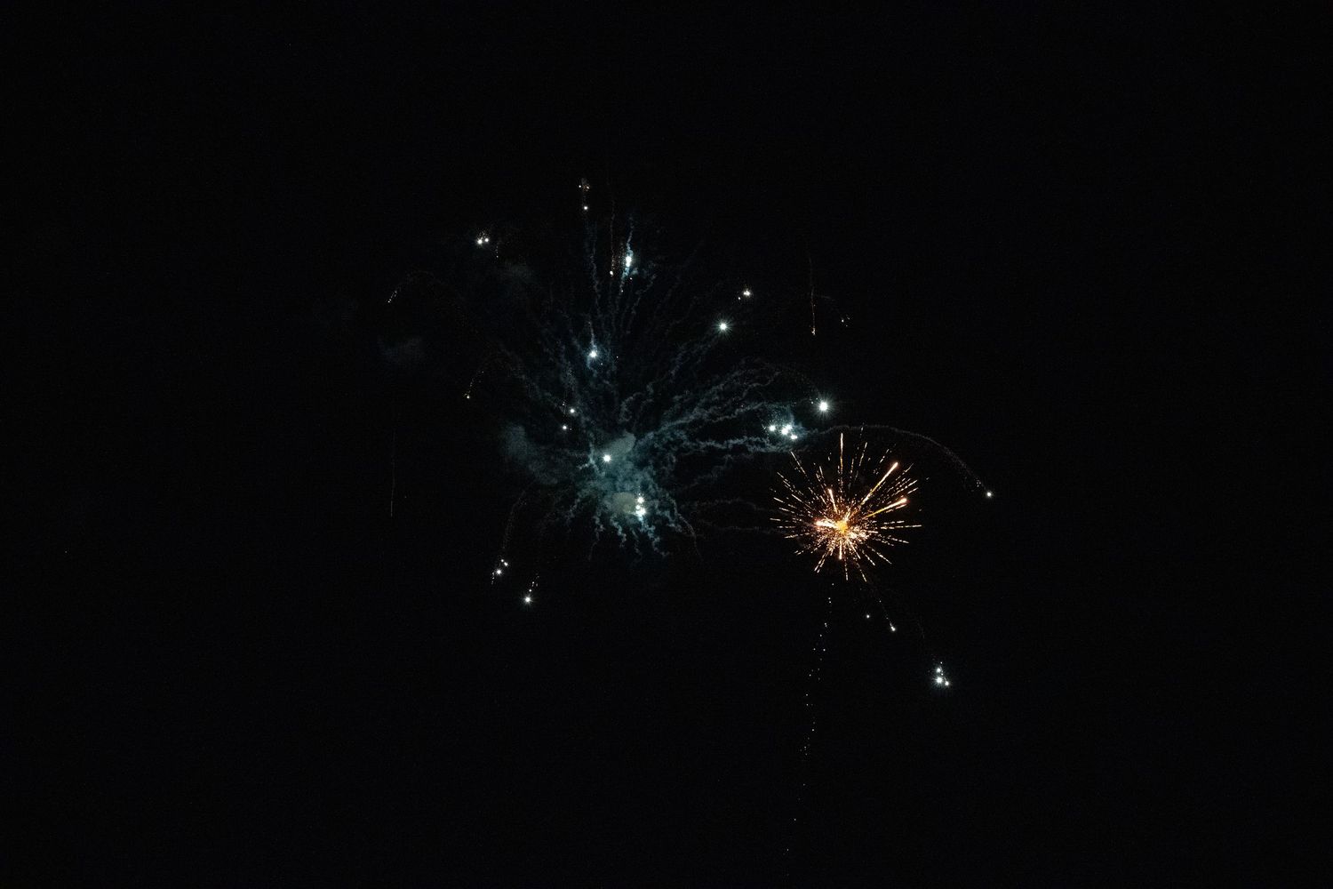 Blue and gold fireworks creating ethereal patterns in the dark night sky.