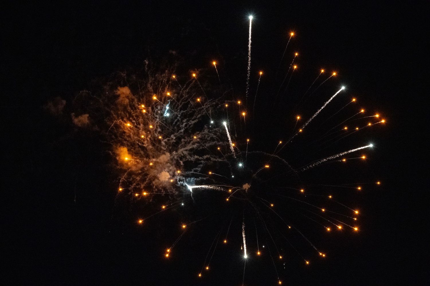 Dramatic gold and white firework explosion with streaming trails of light.