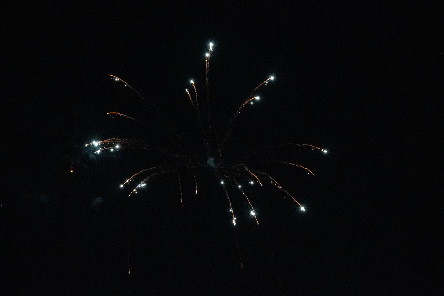 Symmetrical firework burst with blue and orange sparkles against black background.